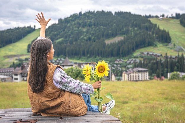 Vrouw met een boeket zonnebloemen in de natuur in een bergachtig gebied