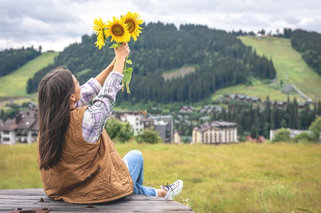 Vrouw met een boeket zonnebloemen in de natuur in een bergachtig gebied