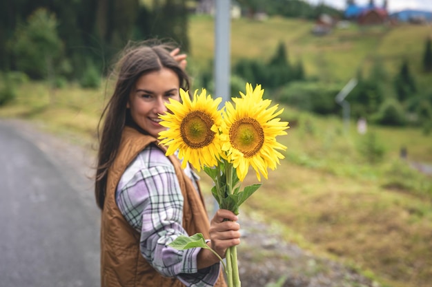 Vrouw met een boeket zonnebloemen in de natuur in een bergachtig gebied