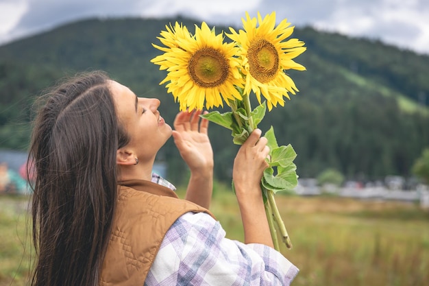 Vrouw met een boeket zonnebloemen in de natuur in een bergachtig gebied