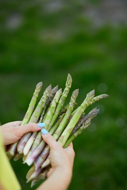 Vrouw met een bos groene asperges in zijn handen buiten