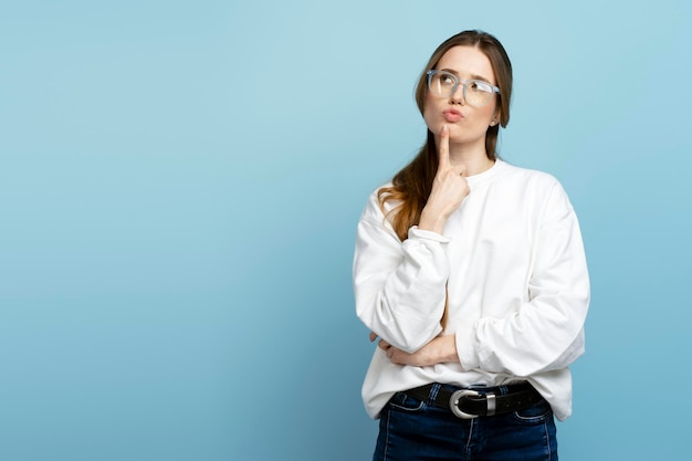 Vrouw met een bril die een idee heeft op zoek naar een oplossing geïsoleerd op een blauwe achtergrond