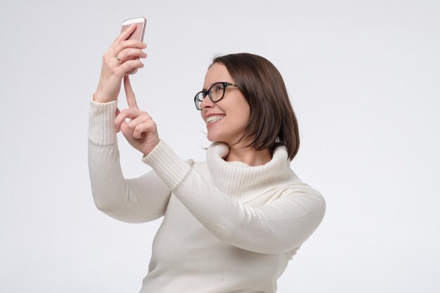 Vrouw met een bril die selfie neemt of een online gesprek voert via de telefoon