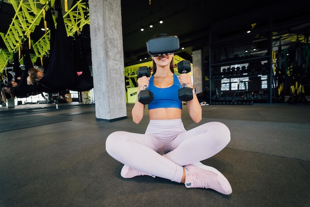 Vrouw met een bril van de virtuele realiteit die traint met halters