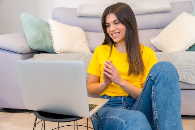 Vrouw met een computer zittend op een bank millennial social media blij met een videogesprek