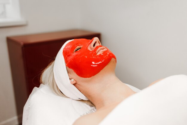 Vrouw met een cosmetisch masker ligt op een stoel in de salon