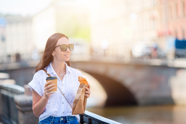 Vrouw met een croissant en koffie buiten op de promenade