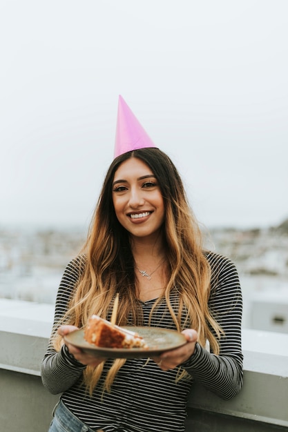 Vrouw met een feesthoed die haar verjaardag viert bij een dak