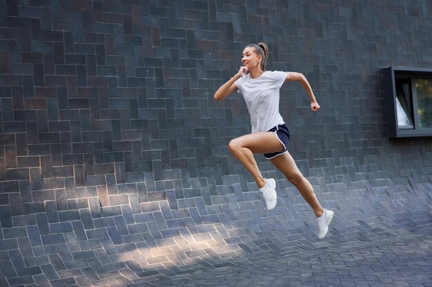 Foto vrouw met een fit lichaam springt en loopt tegen een zwarte muurachtergrond
