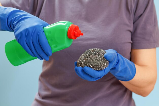 Vrouw met een fles afwasmiddel en een spons op een blauwe achtergrond