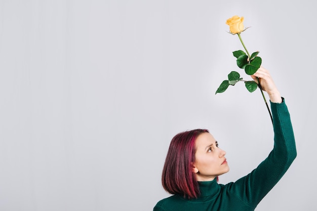 Vrouw met een gele roze bloem in de hand op lichte achtergrond