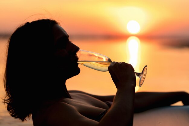 Foto vrouw met een glas champagne op de achtergrond van een prachtige zonsondergang