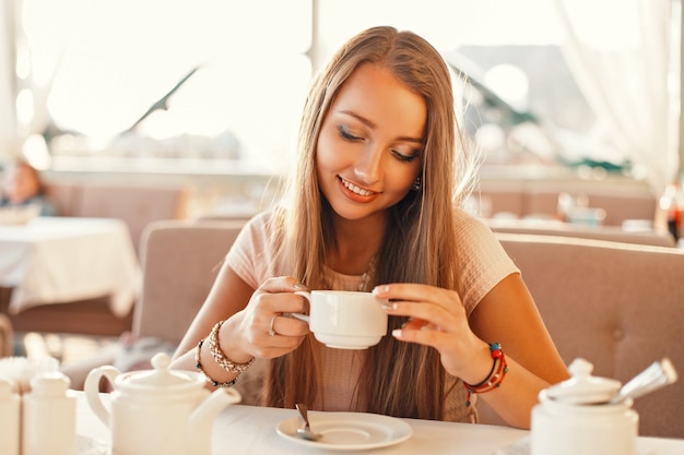 Vrouw met een glimlach die thee drinkt in het restaurant.