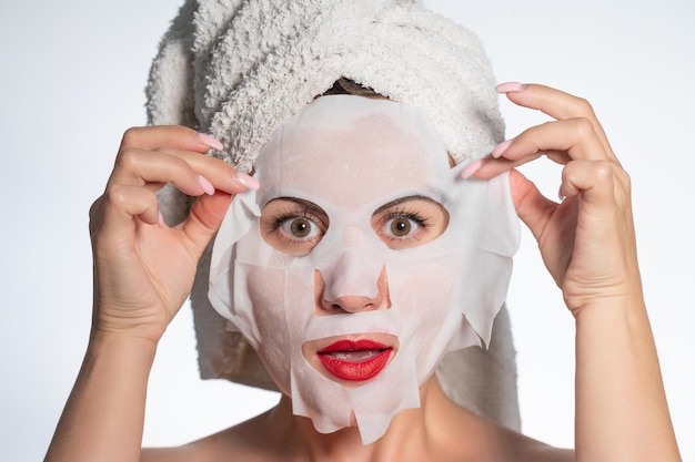 Vrouw met een handdoek op haar haar en een masker op haar gezichtshuid en haarverzorging