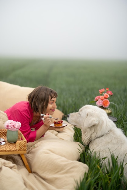 Vrouw met een hond op bed op groen veld buiten