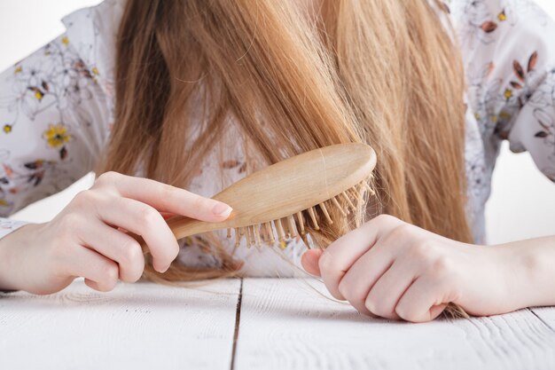 Vrouw met een kam in haar handen probleem haar