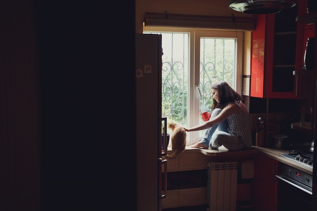 Vrouw met een kat in een venster