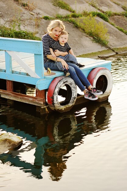 Vrouw met een kind zittend op de brug op de achtergrond van de rivier