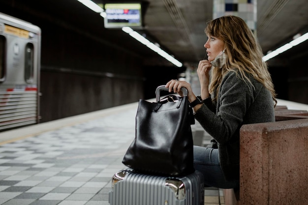 Vrouw met een koffer die op de trein wacht tijdens de coronaviruspandemie