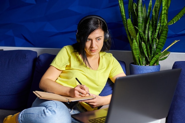 Vrouw met een koptelefoon die online studeert met een notebook