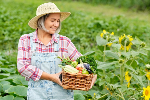 Vrouw met een mand vol oogst biologische groenten en wortel op biologische biologische boerderij. herfst plantaardige oogst.