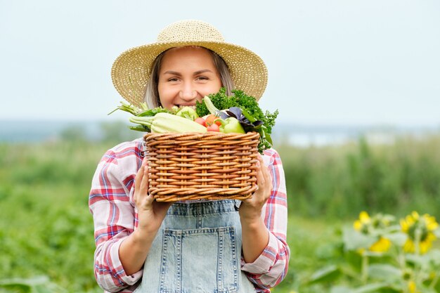 Vrouw met een mand vol oogst biologische groenten en wortel op biologische biologische boerderij. Herfst Plantaardige Oogst.