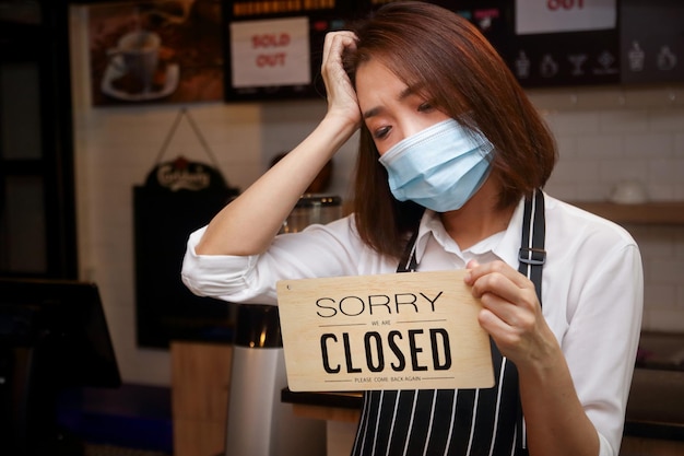 Vrouw met een masker met een gesloten bord in een café