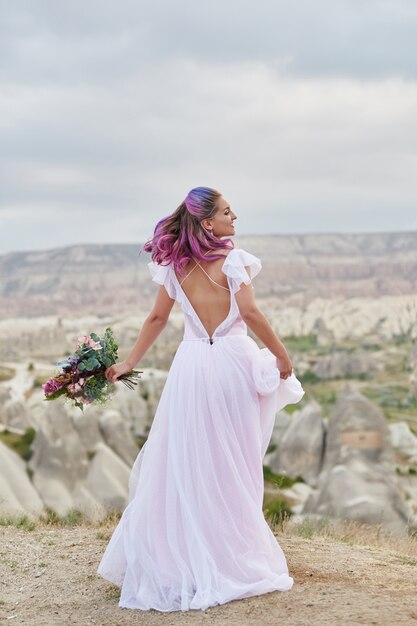 Vrouw met een mooi boeket bloemen in haar handen dansen op de berg in de stralen