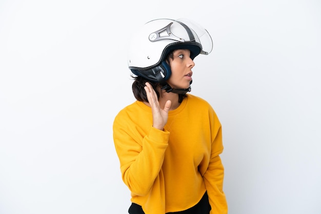 Vrouw met een motorhelm die naar iets luistert door hand op het oor te leggen