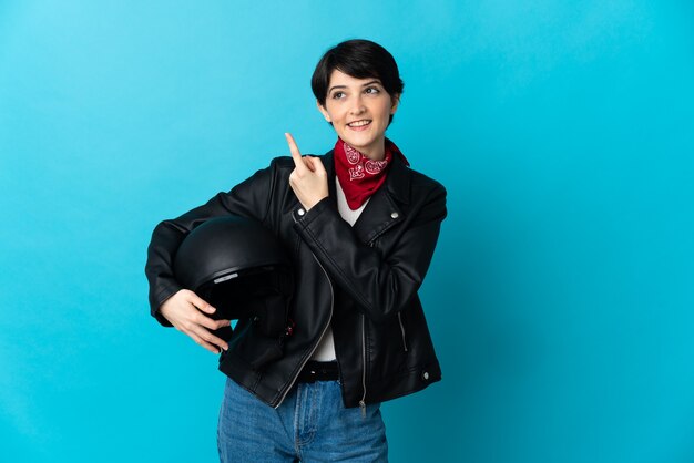 Vrouw met een motorhelm geïsoleerd op blauwe ruimte met een geweldig idee