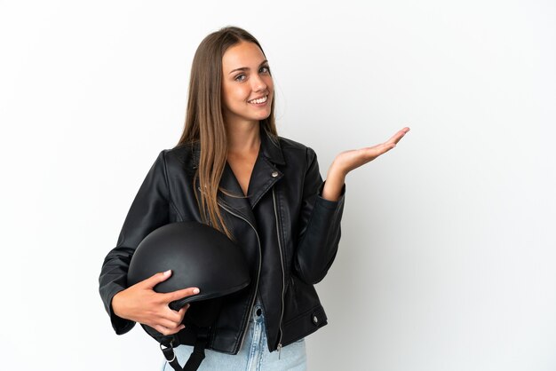 Vrouw met een motorhelm over geïsoleerde witte achtergrond die handen uitbreidt aan de kant om uit te nodigen om te komen