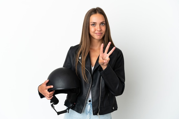 Vrouw met een motorhelm over geïsoleerde witte achtergrond gelukkig en drie tellen met vingers