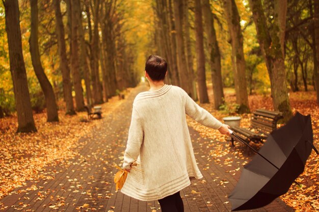 Vrouw met een paraplu loopt in het herfstpark