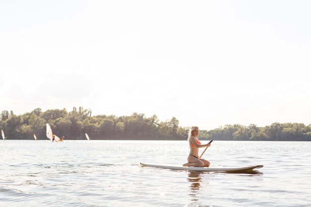 vrouw met een peddel op het bord. benen van een slank meisje op stand-up paddle board.