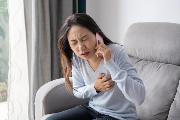 Vrouw met een plotselinge hartaanval die haar borst stevig in het hartgebied houdt, zodat ze onmiddellijk medische hulp nodig heeft, heeft zo snel mogelijk medische hulp nodig Gezondheidsprobleem hartaanvalconcept