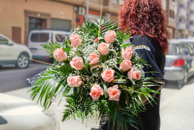 Vrouw met een prachtig boeket bloemen rozenEen boeket rozen wordt vastgehouden door een vrouw op straat