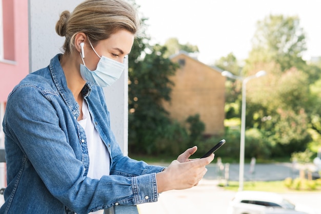 Vrouw met een preventiemasker op haar gezicht gebruikt smartphone