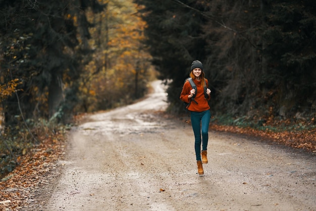 Foto vrouw met een rugzak in volle groei loopt langs de weg in het bos hoogwaardige foto