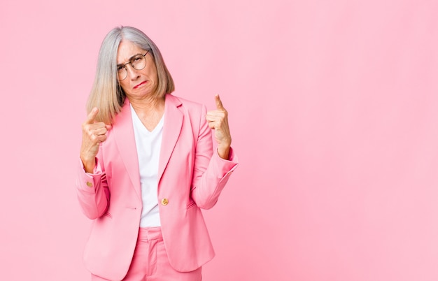 vrouw met een slechte houding die trots en agressief kijkt, naar boven wijst of een leuk teken met handen maakt