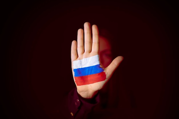 Vrouw met een stopgebaar toont Russische vlag in de palm van haar hand, stop de oorlog