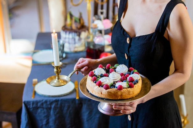 Vrouw met een taart in de buurt van een tafel met kaarsen
