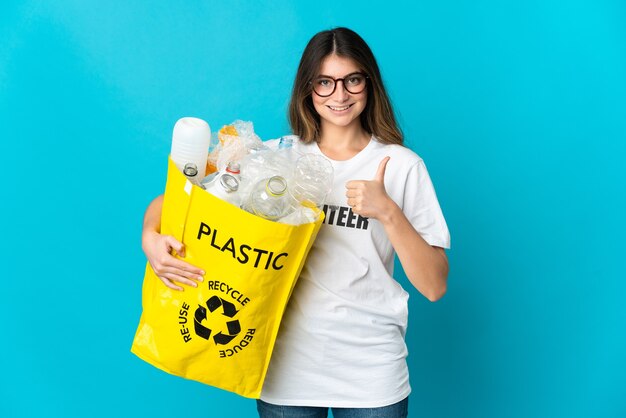 Vrouw met een zak vol flessen om te recyclen geïsoleerd op blauw met een duim omhoog gebaar