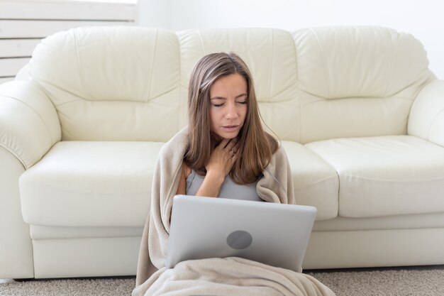 Vrouw met een zere keel zittend op de vloer met laptop