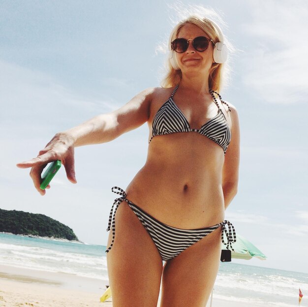 Foto vrouw met een zonnebril op het strand tegen de lucht