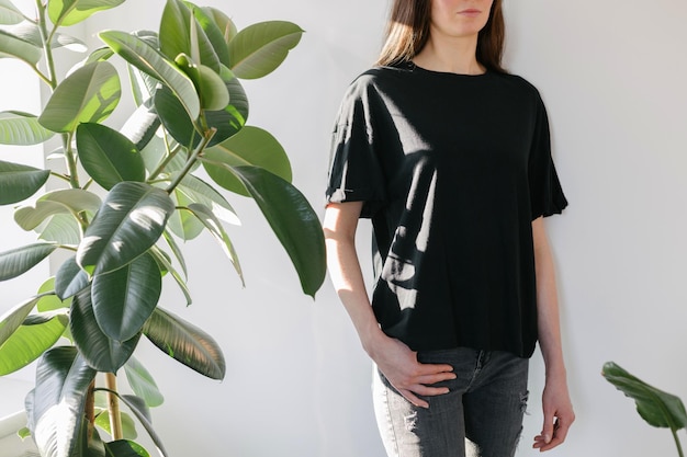 Vrouw met een zwart leeg t-shirt met ruimte voor uw logo, mock-up of ontwerp binnenshuis