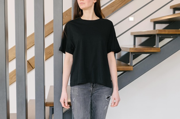 Vrouw met een zwart leeg t-shirt met ruimte voor uw logo, mock-up of ontwerp binnenshuis