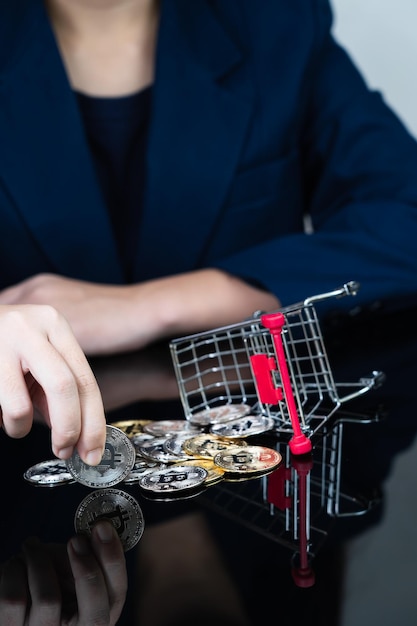 Vrouw met enkele stukjes gouden bitcoin-token in winkelwagen