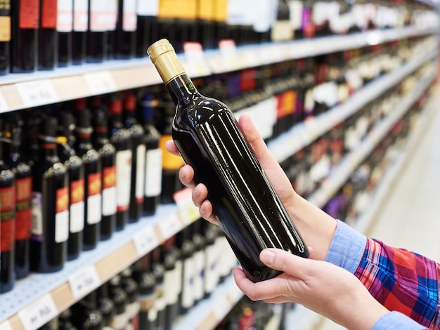 Vrouw met fles rode wijn in de winkel