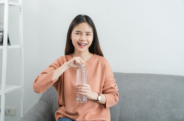 Vrouw met fles water zittend op de bank thuis