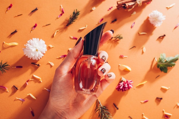 Vrouw met flesje parfum met ingrediënten geur van bloemen, specerijen, kruiden en dennenboom